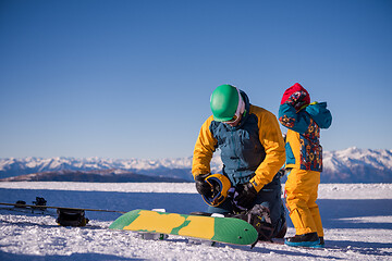 Image showing father preparing his little son for the first time on a snowboar