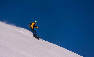 Image showing snowboarder running down the slope and ride free style