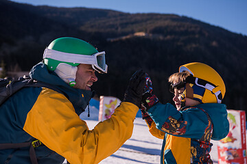 Image showing father preparing his little son for the first time on a snowboar