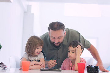 Image showing single father at home with two kids playing games on tablet