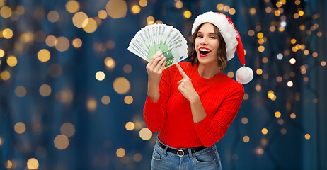 Image showing happy woman in santa hat with money on christmas