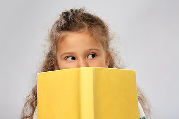 Image showing little girl hiding behind yellow book