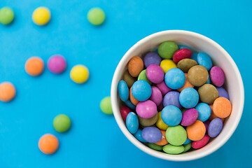 Image showing candy drops in paper cup on blue background