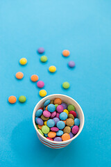 Image showing candy drops in paper cup on blue background