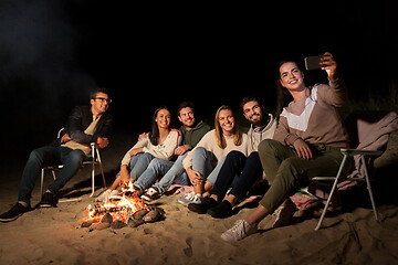 Image showing happy friends taking selfie at camp fire on beach