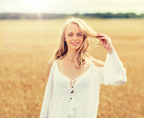 Image showing smiling young woman in white dress on cereal field