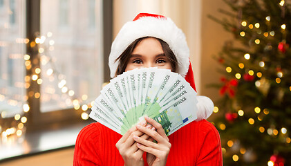 Image showing happy woman in santa hat with money on christmas