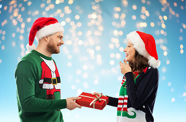 Image showing happy couple in christmas sweaters with gift box