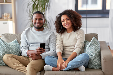 Image showing happy couple with smartphone and earphones at home