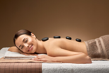 Image showing smiling woman having hot stone massage at spa