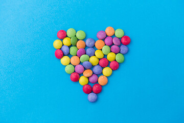 Image showing candy drops in shape of heart on blue background