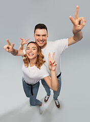 Image showing happy couple in white t-shirts showing peace