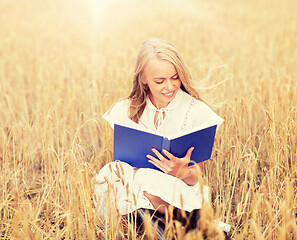 Image showing smiling young woman reading book on cereal field