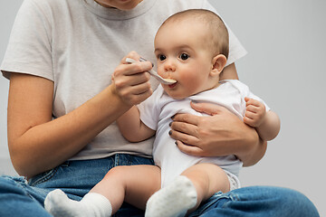 Image showing close up of mother with spoon feeding little baby