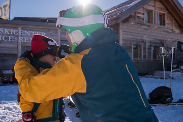 Image showing father preparing his little son for the first time on a snowboar