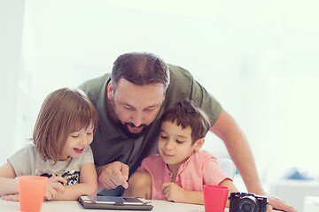 Image showing single father at home with two kids playing games on tablet