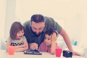 Image showing single father at home with two kids playing games on tablet