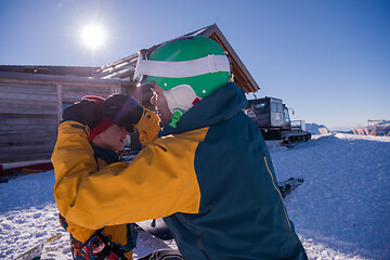 Image showing father preparing his little son for the first time on a snowboar