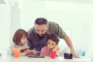 Image showing single father at home with two kids playing games on tablet