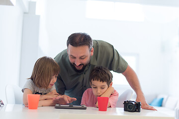 Image showing single father at home with two kids playing games on tablet