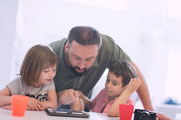 Image showing single father at home with two kids playing games on tablet