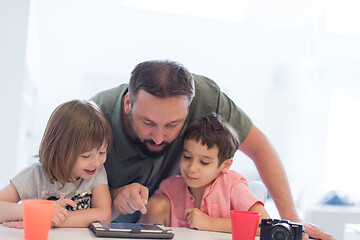 Image showing single father at home with two kids playing games on tablet