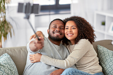 Image showing couple taking picture by selfie stick at home