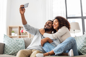 Image showing happy couple with smartphone taking selfie at home