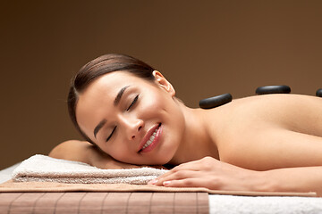 Image showing smiling woman having hot stone massage at spa