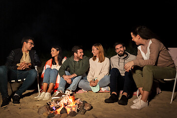 Image showing group of friends sitting at camp fire on beach