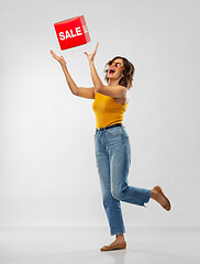 Image showing happy smiling young woman posing with sale sign