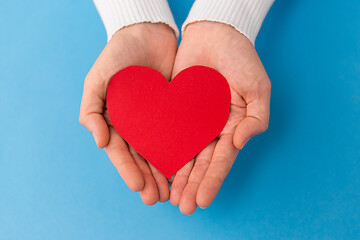 Image showing hands holding red heart shape on blue background