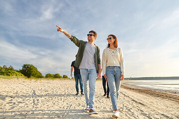 Image showing happy friends walking along summer beach