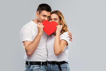 Image showing smiling couple hiding behind big red heart