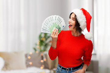 Image showing happy woman in santa hat with money on christmas