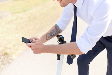 Image showing businessman with smartphone and electric scooter