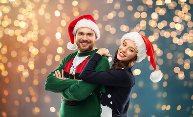 Image showing happy couple in christmas sweaters and santa hats