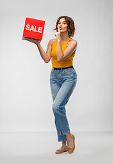 Image showing happy smiling young woman posing with sale sign