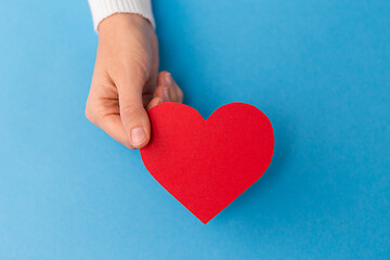 Image showing hand holding red heart shape on blue background