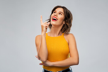 Image showing happy smiling young woman pointing finger up