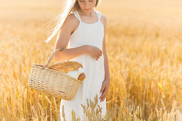 Image showing girl with bread and milk in basket on cereal field