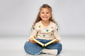 Image showing beautiful smiling girl reading book on floor