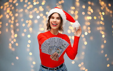 Image showing happy woman in santa hat with money on christmas