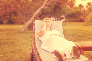 Image showing woman using mobile phone while lying on the sunbed