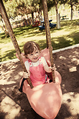 Image showing little girl swinging  on a playground