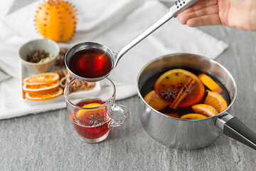 Image showing hand with ladle pouring hot mulled wine to glass