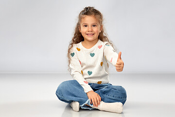 Image showing little girl sitting on floor and showing thumbs up