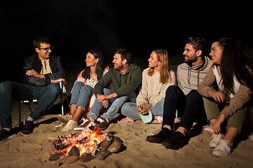 Image showing group of friends sitting at camp fire on beach