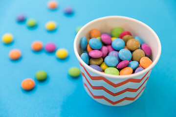 Image showing candy drops in paper cup on blue background