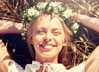 Image showing happy woman in wreath of flowers lying on straw